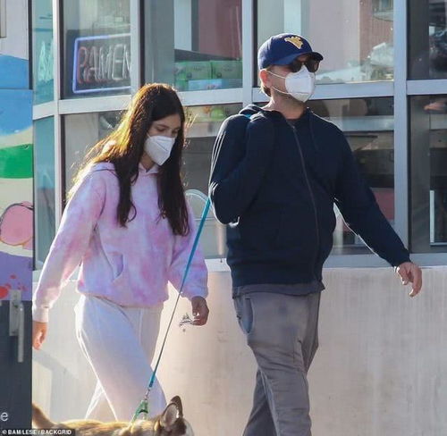 45岁小李子久违出街,戴口罩遛狗,22岁女友同行,穿白裤腿太粗